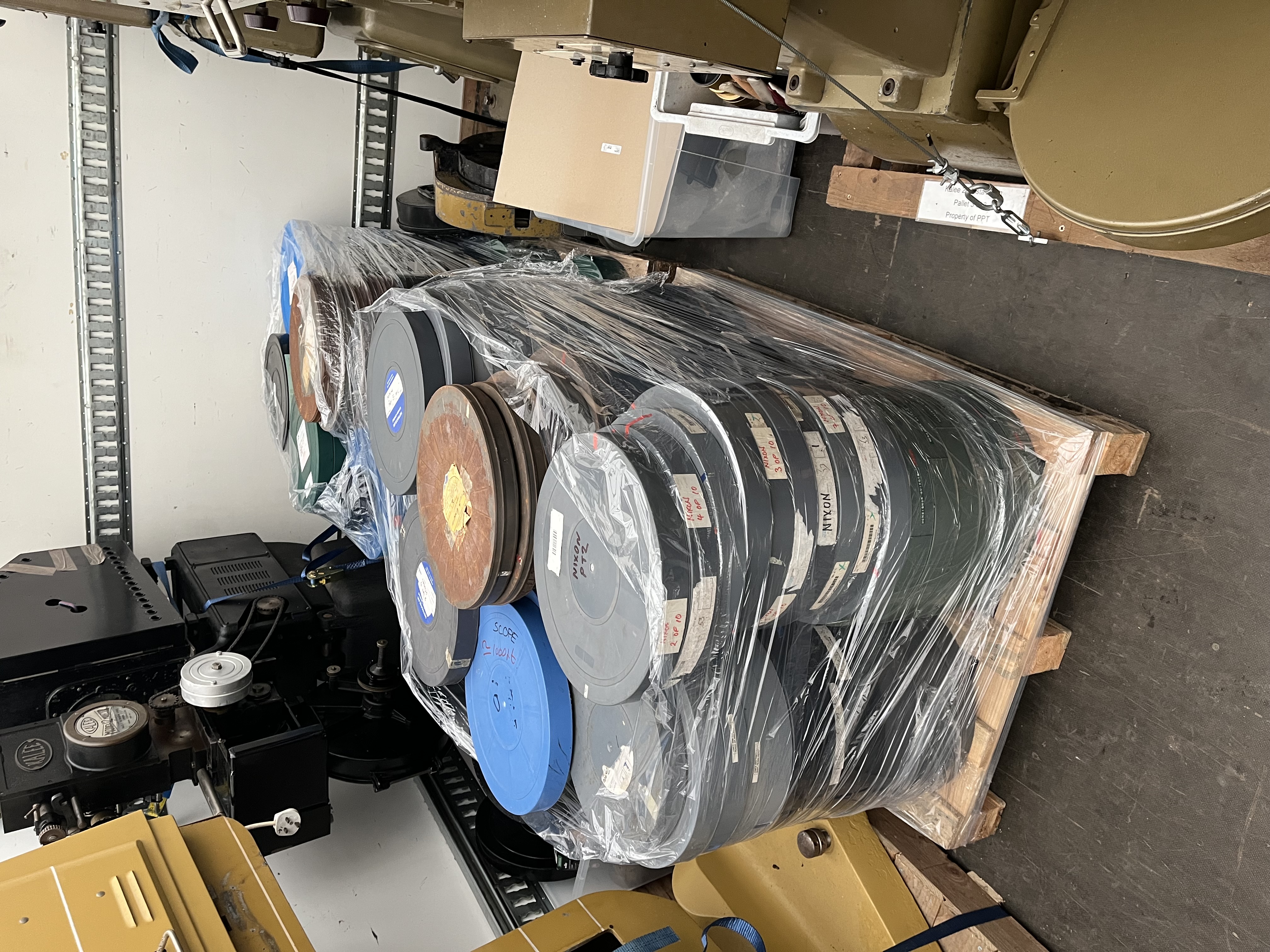 Two wooden pallets with many piles of film cans on top of it.