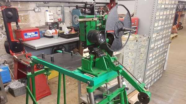 A green film projector mechanism with rotating shutter in front, on a green metal frame.