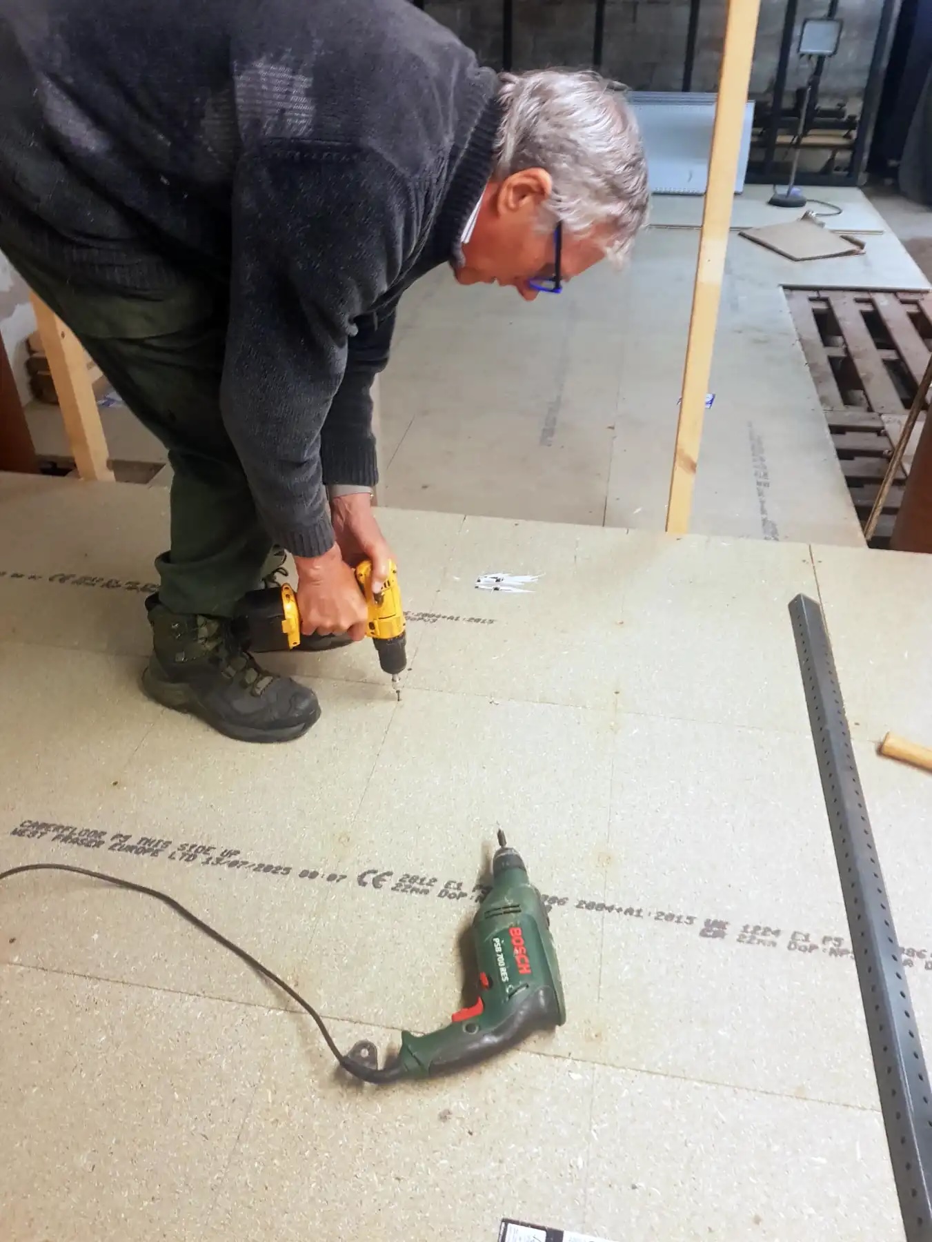 A man screwing in floorboards