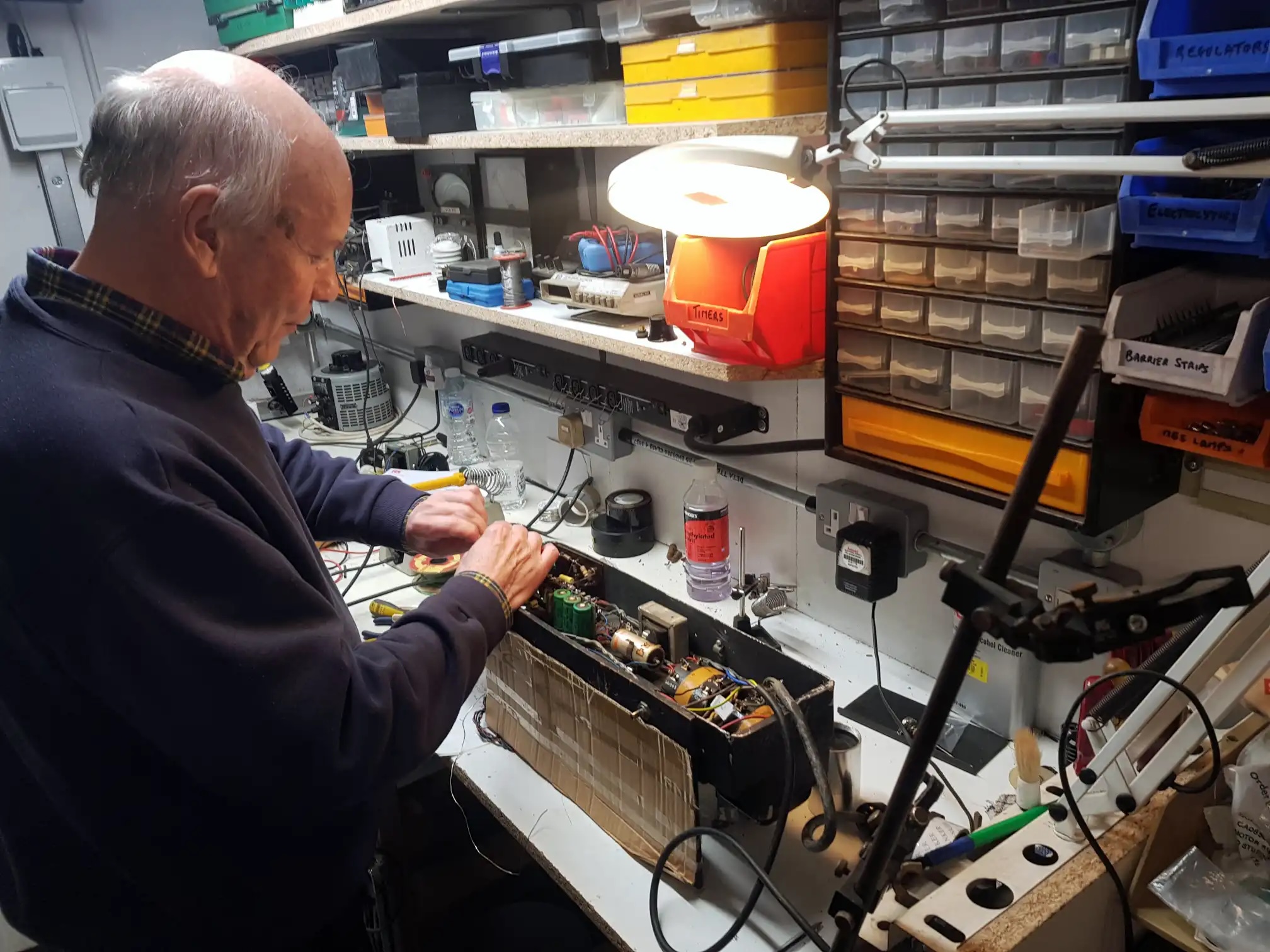 A man at a workbench, repairing electronics