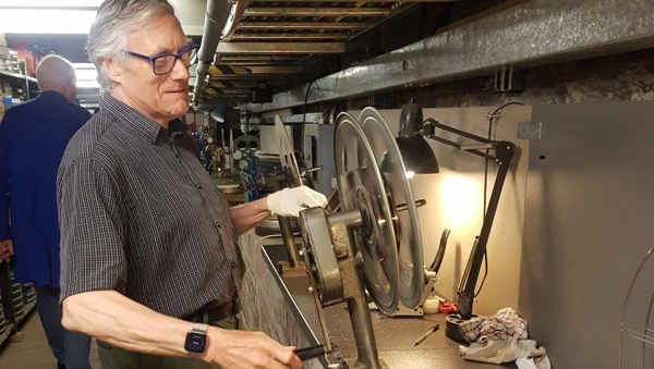 A man standing next to a film rewinder on a bench