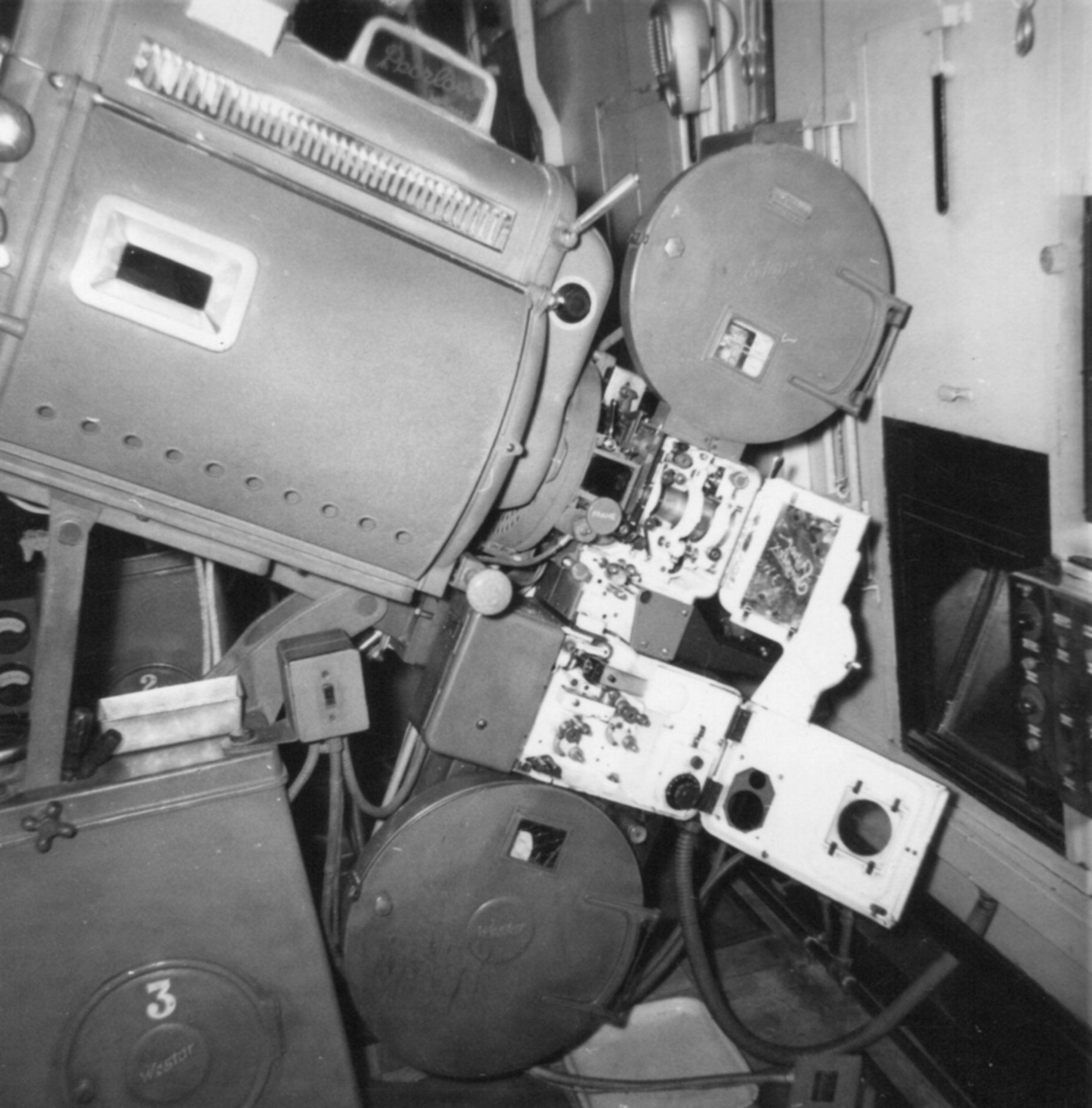 Film projector with lamphouse and spoolboxes. Operator door is open.
