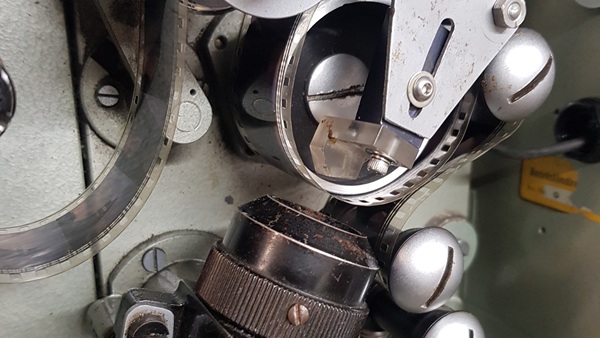 A closeup of the sound drum of a projector, with film threaded over it